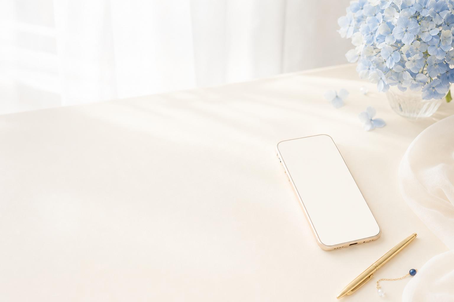 スマートフォンと淡いブルーの花がある明るい机